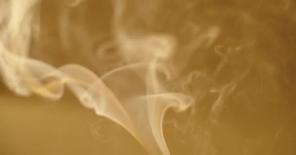 Abstract wallpaper of white smoke steaming up on defocused yellow background slow motion. Vapor rising swirling close up macro view. Mind control meditation concept. Dangerous unhealthy habits — Stock Video