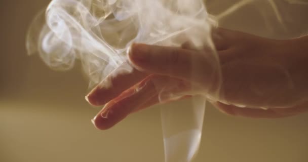 Close-up vrouwelijke hand spelen met witte krullende rook binnenshuis natuurlijk licht slow motion. Gezichtsloze vrouw strelen wierook rook wervelend in zonlicht ondiep gewas uitzicht. Meditatie ontspanning kalmte — Stockvideo