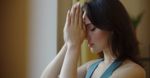 Side view of woman praying god indoors by window slow motion copy space text. Profile portrait of spiritual girl holding joined palms in Namaste close up. Trust hope religion spirit soul practice — Stock Video