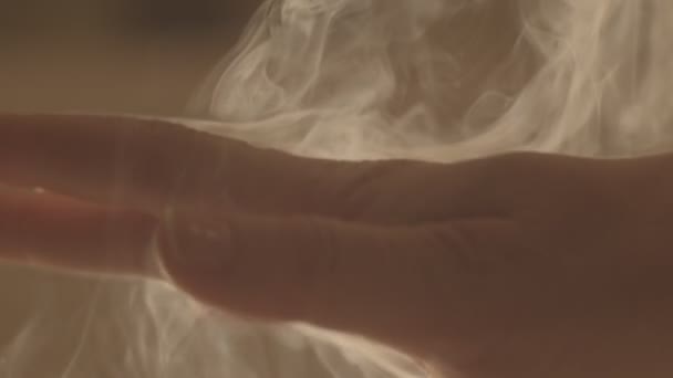 Makro samica ręka delikatnie głaskanie dymu curling zwolnione tempo. Kobieta bez twarzy dotykająca oparów mgły w pomieszczeniu zamyka płytkie pole. Koncepcja relaksu energetycznego opieki zdrowotnej — Wideo stockowe