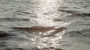 Su yüzeyinde kayan el kamerasıyla güneş dalgaları yavaş çekimde yansıtıyor. Göl üzerindeki uçuş, parlak güneş ışığı yansıması ile dalgalanır. Deniz kağıdı doğa seyahati