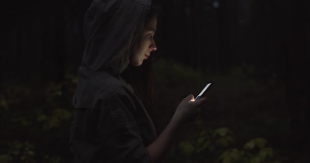 Attraktive Frau nutzt Smartphone im Freien Gut aussehende junge Touristinnen verirren sich in den Wald und sehen sich um, wenn sie den Pfad auf der Karte checken. Studentin mit Kapuze surft im sozialen Netzwerk — Stockvideo