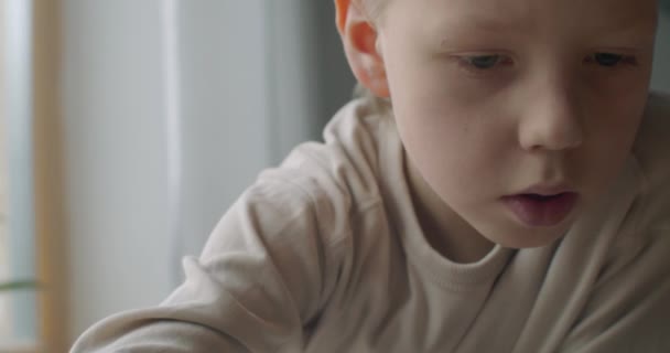 Potret makro dangkal dari anak Kaukasia bermain dengan mainan di dalam ruangan emosi wajah cahaya alami. Menutup anak laki-laki terkonsentrasi membangun bata plastik di meja gerakan lambat detail wajah. Fokus selektif — Stok Video