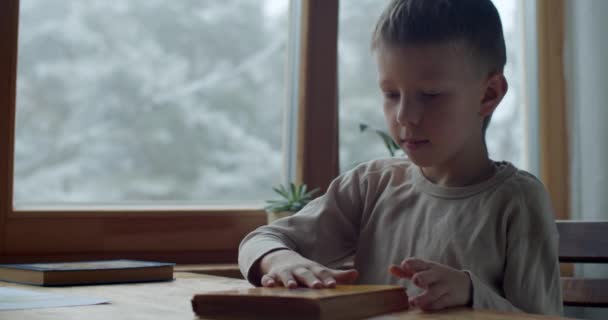 Close up retrato de aluno fechando o livro para leitura em casa fundo janela interior. Jovem cansado de ler livros sentados à mesa dentro de casa. Educação de quarentena atividade de lazer — Vídeo de Stock