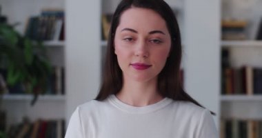 Odanın arka planında kameraya gülümseyen narin kızın portresini yakından çek. Ev üniversitesinde yavaş çekimde poz veren mutlu bayan yönetici öğrencinin ön görüntüsü. Cilt bakımının başarısı 
