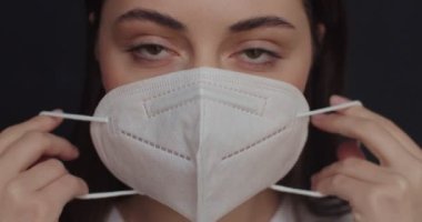 Güzel bir kadın, ikinci bir koronavirüs salgınından korunmak için maske takıyor. Ön manzara makro portresi genç kız kameraya bakıyor virüsten koruyor. Güvenlik Sağlığı Konsepti
