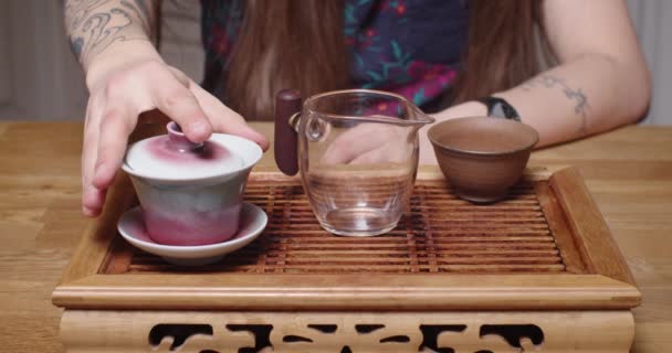 Άσωπος Καυκάσιος δάσκαλος ρίχνει ζεστό τσάι στην κινεζική τελετή αργή κίνηση. Μπροστά όψη του ανθρώπου που κάθεται στο ξύλινο τραπέζι chaban ζυθοποιίας πράσινο Oolong puer χρησιμοποιώντας την παραδοσιακή υπηρεσία υγιεινής. Πολιτισμός της Ανατολής — Αρχείο Βίντεο