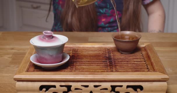 Tăiat aproape împușcat de maestru ceai turnarea apei de ceai în castron. Vedere din față a omului care prepară băutură fierbinte oolong pe chaban de masă din lemn la bucătărie. Ceremonia chineză orientală pregătește conceptul — Videoclip de stoc