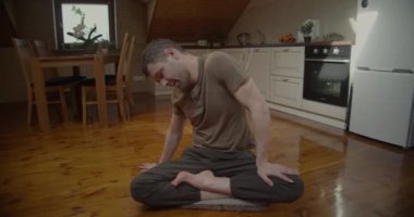 Evdeki yavaş çekimde yoga yapan bir adamın ön görüntüsü. Yogacı adam Asya 'da bağdaş kurup sabah egzersizi yapıyor. Sağlıklı yaşam tarzı alışkanlıkları kavramı