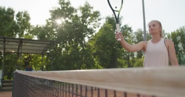Zwei Tennisspieler beginnen ein Match, das im Freien am Netz auf dem Tennisplatz stattfindet. Attraktive Frauen mit erhobenen Schlägern grüßen einander im Zeitlupentempo. Freundschaftsrespekt — Stockvideo