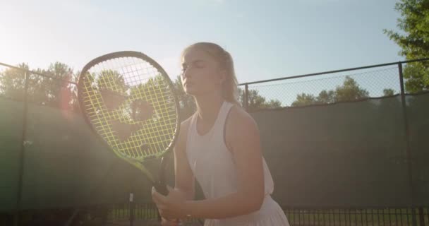 O femeie puternică în formă, în picioare cu rachetă, așteptând mingea de tenis care arată concentrată și serioasă. Jucător profesionist de sex feminin care practică sport activ lent mișcare raze calde de vară. răbdare de anduranță — Videoclip de stoc