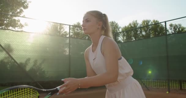 Garota determinada esperando com raquete na mão no fundo do tribunal câmera lenta. Retrato de mulher jogadora séria recebendo a bola enquanto torneio de tênis. Concentração da determinação da paciência — Vídeo de Stock