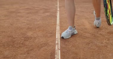 Spor ayakkabılı güçlü kadın bacakları. Yaklaş. Yüzü olmayan sporcu kadın tenis maçından önce ısınıyor. Spor aletleri ayakkabı raket topu konsepti