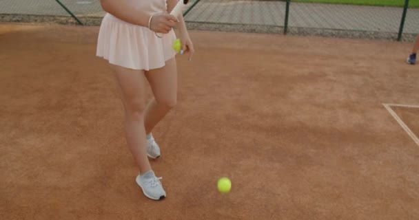 Професійна спортсменка, що подає тенісний м'яч супернику на глиняному дворі на відкритому повітрі літнього фону. Молода дівчина спортсменка грає в теніс, що практикує перемогу. Знімок способу життя хобі — стокове відео