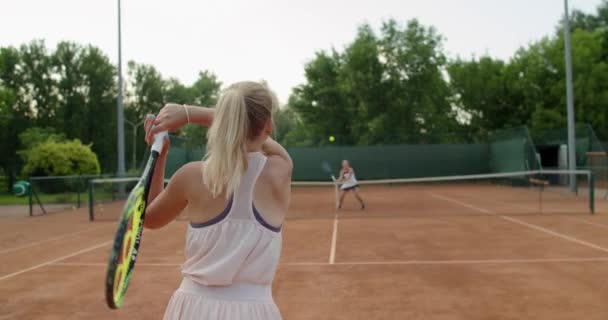 プロのスポーツウーマンは、夏の屋外のクレイコートで対戦相手にテニスボールを提供しています。屋外でテニスの練習をしている女の子。スポーツウェア機器アクティブライフスタイル — ストック動画