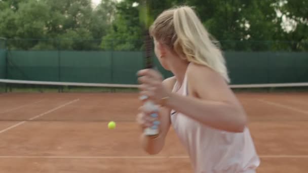 Pohled zezadu na dvě silné sportovkyně hrající v létě tenis venku na hliněném hřišti. Nerozpoznatelné blondýny dívka hráč hity obdrží míč při tréninku cvičení sportu. Zdravotní péče o tělo — Stock video