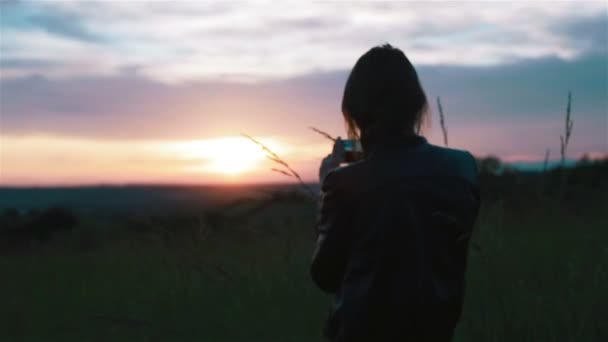 若い女性は、スマート フォンで夕日の写真を撮る。ロング ショットとクローズ アップ — ストック動画