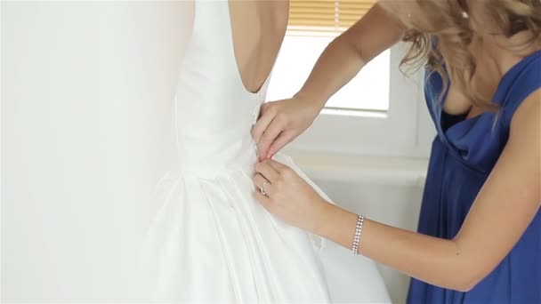 Brautjungfer hilft Braut, Brautkleid zu knöpfen