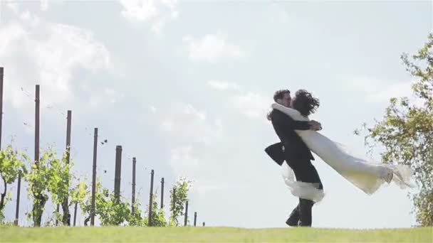 Noivo girando noiva ao redor e beijando a mão perto de vinhas na Itália — Vídeo de Stock