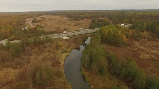 4k Luftaufnahme - Flug über Autobahn mit Fluss und bunten Herbstwäldern auf beiden Seiten — Stockvideo