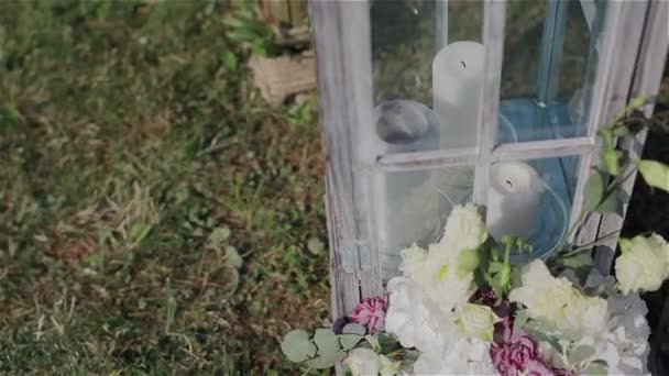 Decoración de la boda de la boda al aire libre. Velas blancas y flores en el jardín. Primer plano. Pan tiro — Vídeo de stock