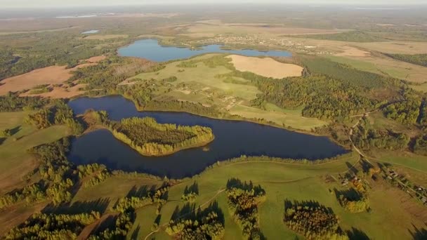 Vue aérienne 4K survolant de beaux lacs bleus et des champs récoltés à la campagne par temps ensoleillé couleurs d'automne 