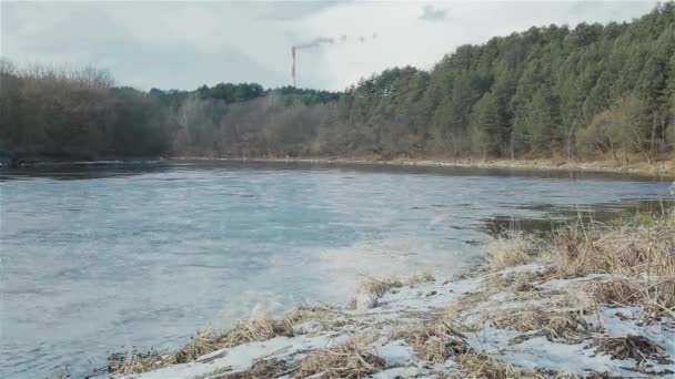 Зимовий краєвид на березі річки з димохідним заводом позаду — стокове відео