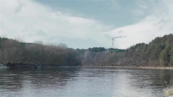 Winterlandschap van de rivier met een schoorsteen roken fabriek achter — Stockvideo