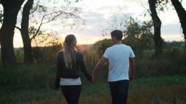 Günbatımında alanına yürüyor elele aşık genç bir çift. Ağır çekim