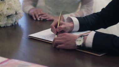 Gelin ve damat evlilik cüzdanını imzalıyor. Close