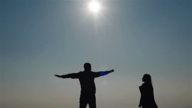 Gökyüzü ve deniz bir arka plan üzerinde kucaklayan mutlu genç çift siluet. Adam ellerini etrafında kadın etrafında dönen