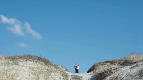 Para stoi i rozmawia na szczycie piaszczystej wydmy pod pięknym czystym błękitnym niebem — Wideo stockowe
