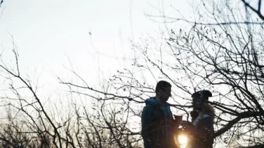 Genç ve güzel çift bardaklarını tokuşturarak romantik bir günbatımı ortamında konuşuyor ve öpüşüyorlar.