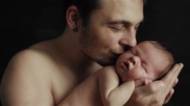 Sevgi dolu genç baba şefkatle elinde sevimli uyuyan yeni doğan bebek oğlu onu öpme tutarak