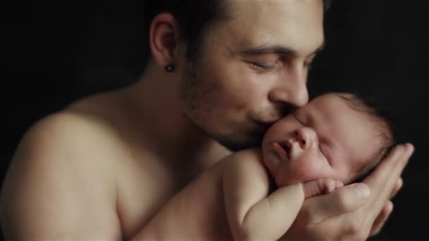 Amoroso joven padre tiernamente sosteniendo en sus manos adorable durmiendo recién nacido hijo besándolo — Vídeos de Stock