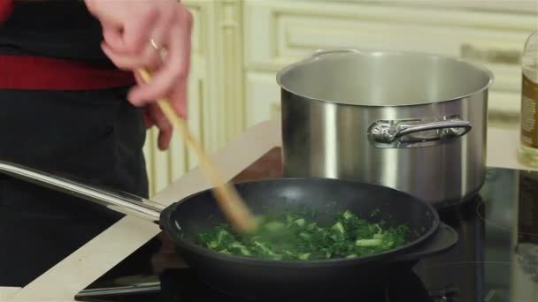 Profesjonalny kucharz ręce mieszania szpinak i cebuli na patelni. Szczelnie-do góry — Wideo stockowe