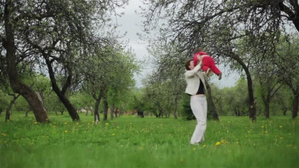 Madre sosteniendo a su hija jugando en el huerto de verano — Vídeos de Stock