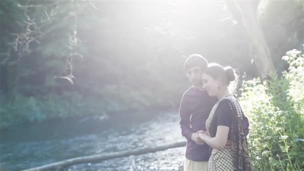 Junges Paar, das am Ufer des Flusses steht und sich umarmt. Mittelschuss. Sommerlandschaft — Stockvideo