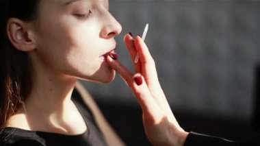 Profesyonel makyaj sanatçısı için model dudaklar dudak parlatıcısı uygulayarak. Yakın çekim