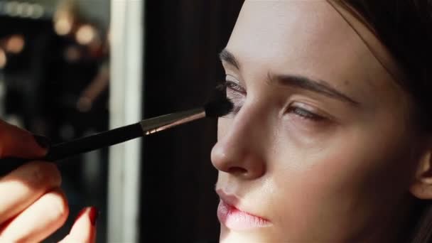 Maquillador profesional que utiliza un pincel para aplicar la base a la cara del modelo. Primer plano — Vídeo de stock