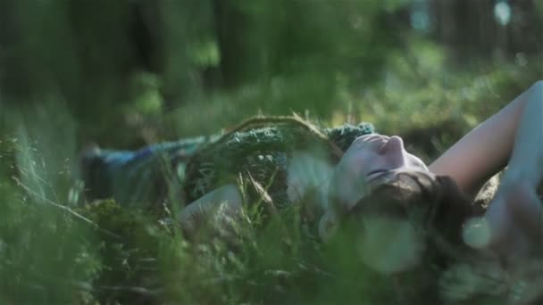 Jeune femme dans la forêt couchée sur la mousse et touchant les plantes autour d'elle. Gros plan — Video