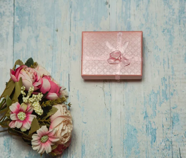 青い木の背景に美しい花花束とピンクのギフトボックス — ストック写真