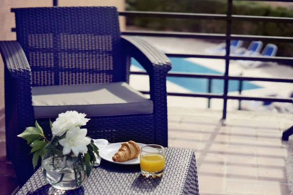 Komodinin yanında pembe çiçekli vazo ve kitapla süslenmiş..