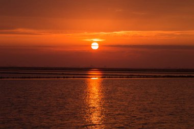 Donana 'da dramatik bir gökyüzü. Kırmızı ve turuncu bir sabahta pirinç tarlasına yansıyan güneş