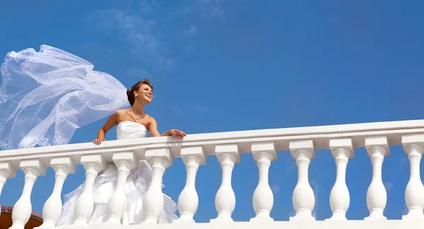 Felice sposa sorridente in un lungo velo in piedi sulla terrazza — Foto Stock