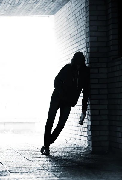 Teenager holding a beer bottle and standing in the alley — Stock Photo, Image