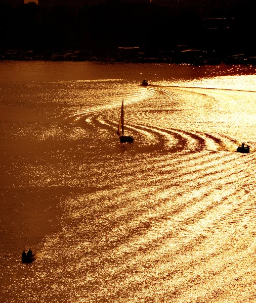 Silhuetas de pequenos barcos no rio nos raios do pôr do sol — Fotografia de Stock