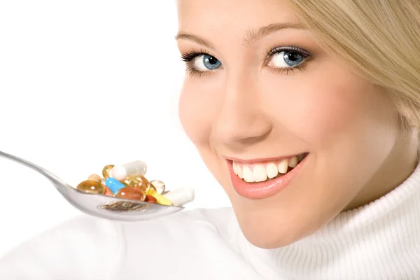 Mujer joven sonriente comiendo un montón de pastillas en cuchara — Foto de Stock