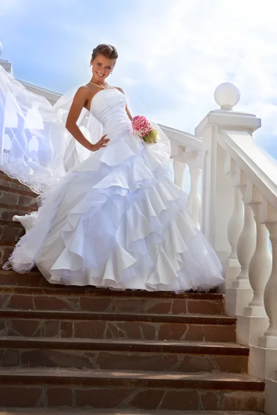 Beautiful bride standing on stairs in the sunny day — Stock Photo, Image