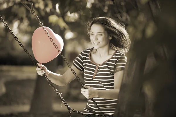 Balanceo con un globo en forma de corazón rojo —  Fotos de Stock